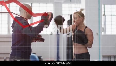 Punching boxer on right wearing black gloves and leggings, striking focus mitts in gym, copy space Stock Photo