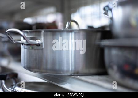 Stainless steel pots on shelf in commercial kitchen, professional cooking equipment setup Stock Photo