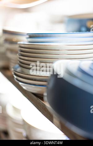 Stacked ceramic plates on wooden shelf in modern kitchen, clean minimalist design Stock Photo