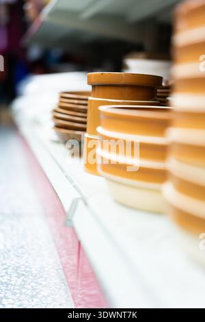 Stacked ceramic bowls on display shelf in a market stall, blurred background with urban setting, Stock Photo