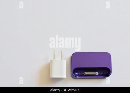 Various iPhone and iPad chargers, cables, and power adapters arranged on a clean white table. Concept of mobile technology, charging accessories Stock Photo