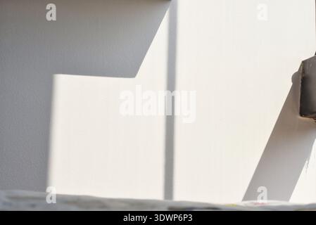 Sunlight entering through a window creating warm natural light and soft shadow patterns on a wall, minimalist interior scene with peaceful and cozy Stock Photo