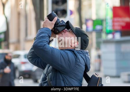 50 year old man with camera photographing buildings on Austrian street. Stock Photo