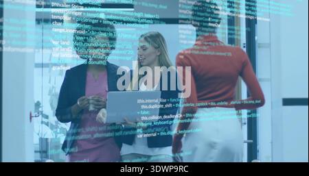 Pointing three women discussing code on glass partition in office, holding laptop and cup, red top Stock Photo