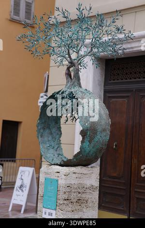 Bronze sculpture of a tree emerging from a hollow spherical base with verdigris patina, displayed on a stone pedestal in Nice's old town.Nice,France Stock Photo