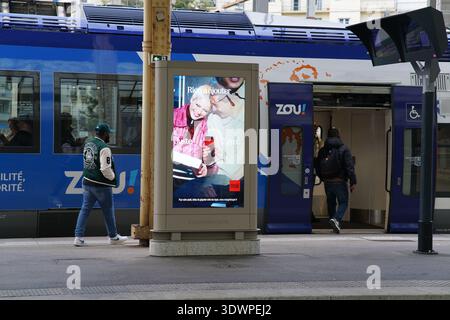 Large platform billboard at Nice train station advertises Zou's "Plaisir d'hiver" campaign with a joyful elderly couple enjoying hot drinks Stock Photo