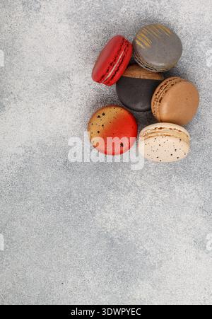 Assorted multicolored macaroon cookies on a gray concrete background close-up. Sweet French macarons biscuits. Desert for gourmets. Selective focus, t Stock Photo