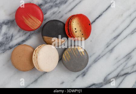 Assorted multicolored macaroon cookies on a marble background close-up. Sweet French macarons biscuits. Desert for gourmets. Selective focus, top view Stock Photo