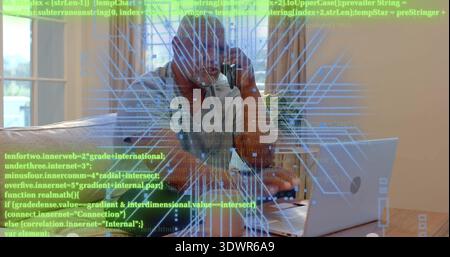 Holding smartphone senior wearing glasses and shirt typing on laptop at table, with code overlay Stock Photo