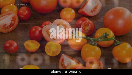 Showing red and yellow tomatoes halved and whole, resting on rustic wood table, vine, timestamp Stock Photo