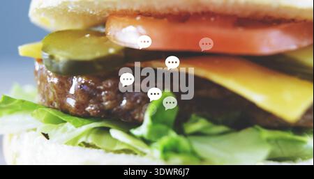 Displaying burger in studio with bun, lettuce, patty, melted cheese, tomato, pickles speech-bubbles Stock Photo