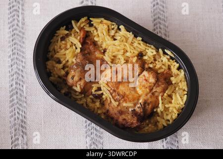 Chicken with rice in a black container on a light tablecloth Stock Photo