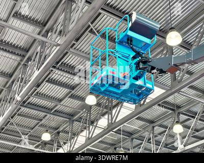 Construction crew using aerial lift to inspect high ceilings in a large warehouse during daytime work hours Stock Photo