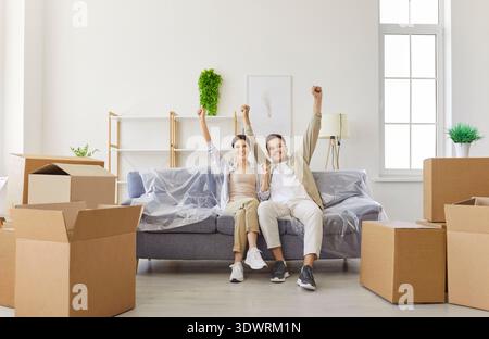 Happy young couple celebrating new home purchase and moving with hands up Stock Photo