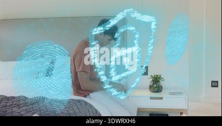 Using device, man in rust T-shirt leaning on bed in modern bedroom, with security hologram Stock Photo