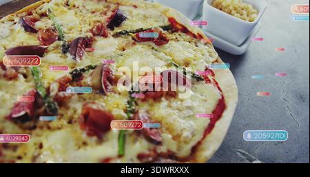 Showing whole pizza on wooden board on grey countertop, with small white bowl and digital tags Stock Photo