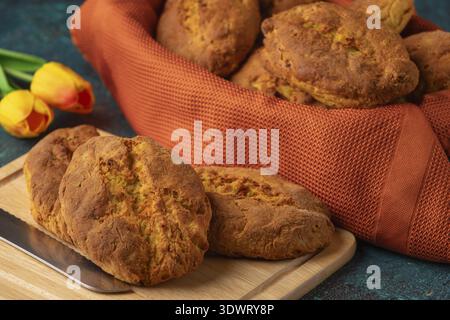 Fresh potato rolls in a basket with orange cloth, some on a wooden board Stock Photo