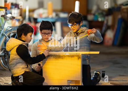 Children learning carpentry skills working together on project Stock Photo