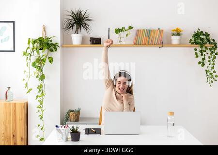 Young adult businesswoman celebrating victory at home office Stock Photo