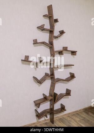 Modern tree shaped wooden bookshelf on white wall, designer wall mounted book  Stock Photo