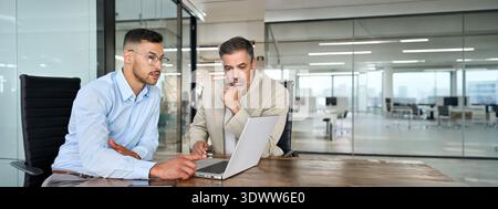 Two busy business men working using laptop computer in office thinking on data. Stock Photo