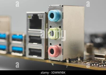 audio jack housing on motherboard surface, blue green and pink plastic connectors with silver ethernet port, closeup soft focus, peripheral Stock Photo