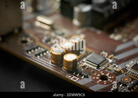 gold and silver capacitors on brown printed circuit board or motherboard surface, closeup with soft focus, computer hardware technology and electronic Stock Photo