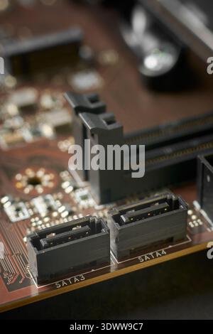 two black plastic sata connector sockets on motherboard surface, metallic pins and electronic components, closeup with soft focus, data storage Stock Photo