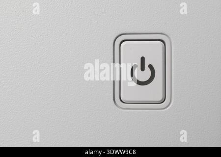 rectangular white plastic power button on textured white pc casing, black power icon symbol, top view closeup with copy space, technology interface Stock Photo