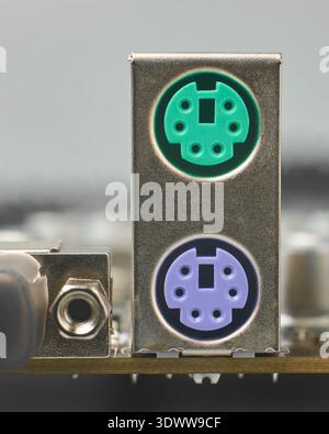 silver metallic ps2 housing on motherboard, green and purple plastic ports for mouse and keyboard, closeup with soft focus, legacy computer hardware Stock Photo