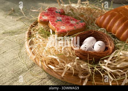 Traditional Easter bread with festive bunny cookie and decorative nest with eggs in rustic spring setting Stock Photo