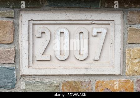 Stone plaque engraved with the year 2007 set into a multicolored masonry wall, showing weathered texture and architectural detail useful for construct Stock Photo