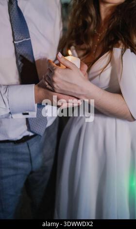 Happy newlyweds holding a burning candle Stock Photo