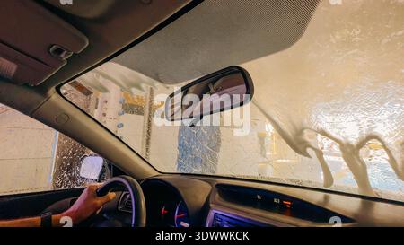 Santa Maria, California, USA. July 26, 2024. Inside view of a car being washed, with suds and water covering the glass. Stock Photo