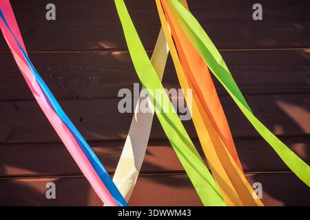 Spring festival vibrant satin ribbons crossing over a dark wooden wall background with copy space. Stock Photo
