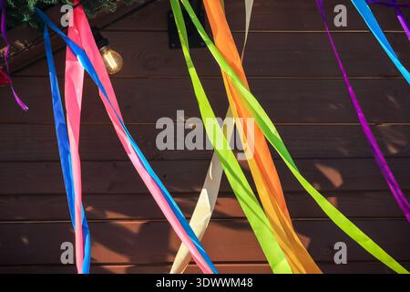 Spring festival vibrant satin ribbons crossing over a dark wooden wall background with copy space. Stock Photo