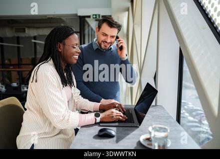 Diverse business professionals collaborating on laptop in modern office Stock Photo