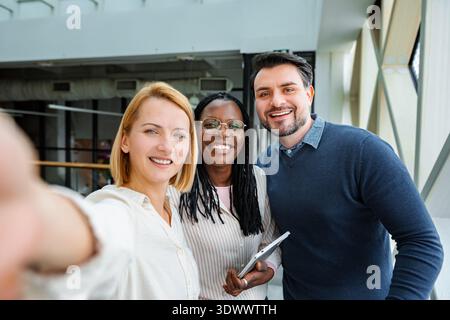 Diverse business team taking selfie in modern office Stock Photo