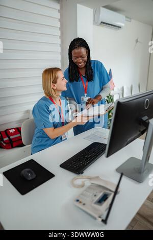 Two nurses collaborating on patient care at a reception desk Stock Photo