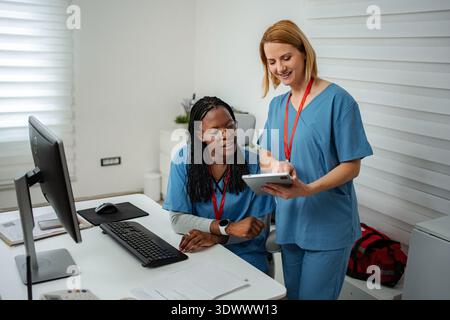 Nurses collaborating on digital tablet in modern medical office Stock Photo