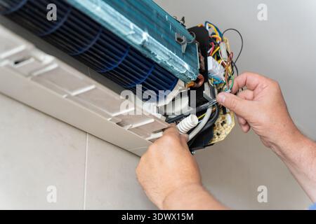 A male air conditioner technician or air conditioning installation. technician is about to repair air conditioning in homes and buildings. Stock Photo