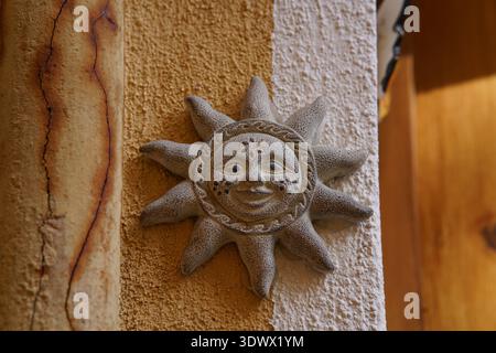 Smiling sun face ceramic plaque mounted on textured wall in Mediterranean style. Menton, France Stock Photo