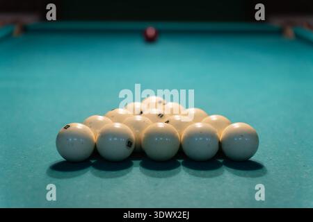 The white balls are arranged in a triangle on a green snooker table before the first shot at the start of the game Stock Photo