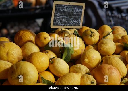 Fresh yellow lemons piled high with leaves at Provence market stall priced 2.90€/kg.Menton,France Stock Photo