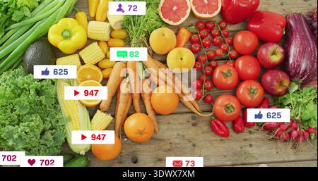 Displaying produce spread on wooden table, with carrots, oranges, avocado, social-media icons Stock Photo