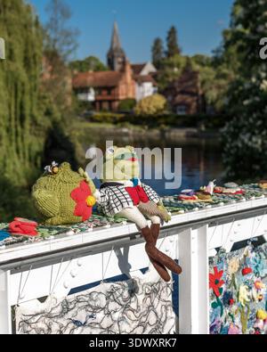 Yarn bombing art featuring knitted Mr Toad frog on bridge railing over the River Thames and view of St Mary's Church in Whitchurch-on-Thames Stock Photo