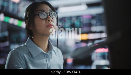 Professional Woman Takes Seat at Desk, Stands Digital Tablet to Side Before Starting Workday and Begins Processing Complex Stock Market Data and Analyzing Real Time Charts Across Multiple Monitors. Stock Photo