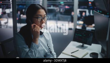 Professional Woman Experiences Wrist Pain and Fatigue From Prolonged Keyboard and Mouse Use. Female Picks Up Corporate Landline Phone Discuss Market Data While Monitoring Real Time Financial Charts. Stock Photo