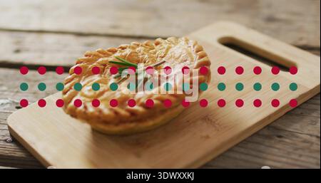 Displaying two stacked savory pies on wood board with handle, rosemary topping pies, red teal dots Stock Photo