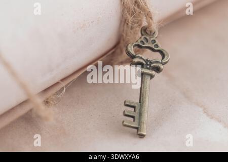 Retro key on jute rope on grunge brown paper background. Vintage style card with copy space. Stock Photo